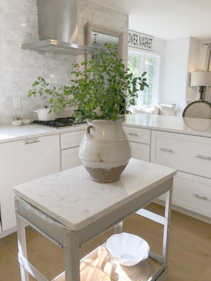 Serene tranquil white kitchen with farm sink, marble subway tile, Viatera Minuet quartz counters, white Shaker cabinets, and white oak flooring. Design and photo: Hello Lovely Studio. #kitchendesign #whitekitchen #minuet #whitequartz #benjaminmoorewhite