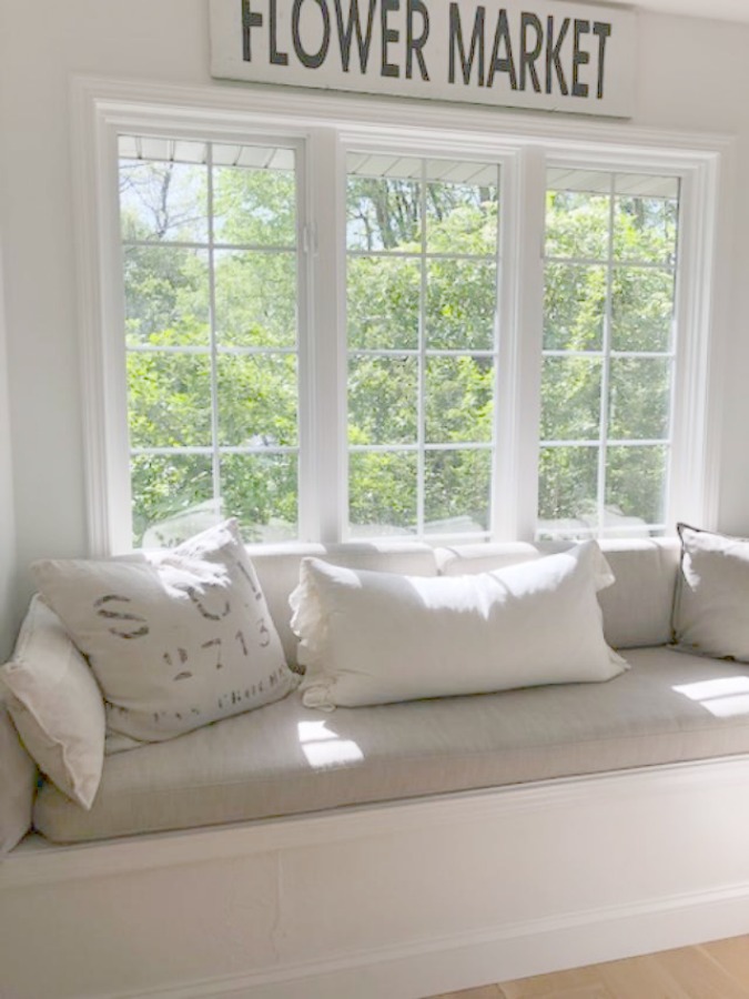 Hello Lovely's kitchen window seat with linen pillows and cushion and Flower Market sign above windows.
