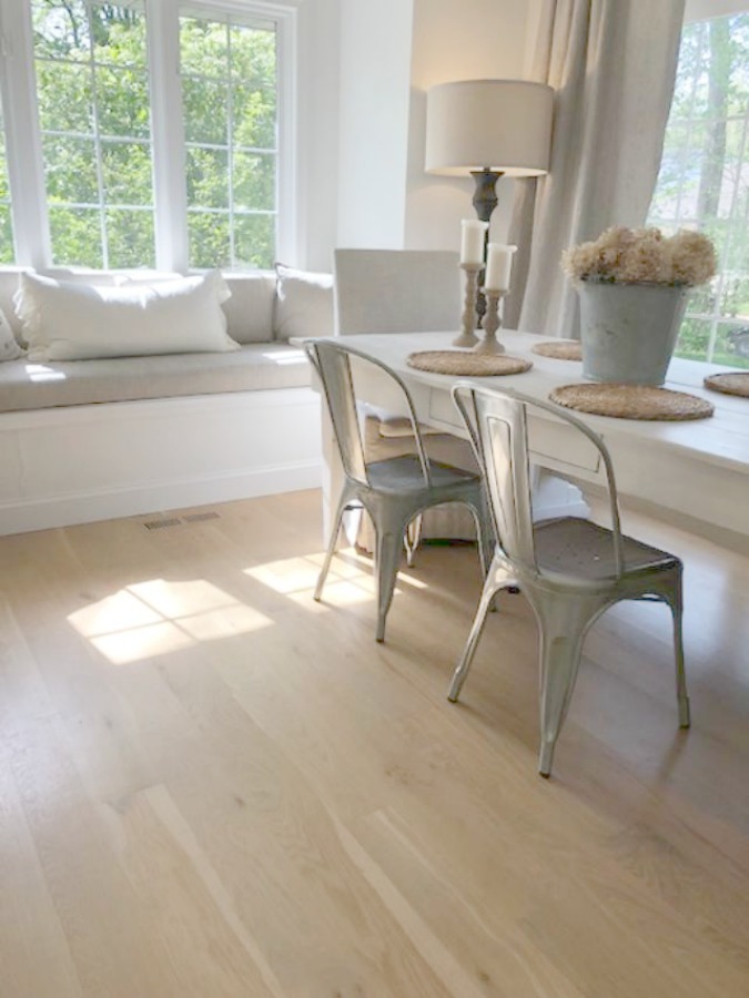 Hello Lovely's European country breakfast nook with harvest table, metal Industrial chairs, window seat, and white oak hardwood flooring.