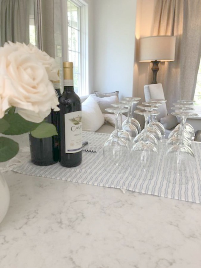 Serene tranquil white kitchen with farm sink, marble subway tile, Viatera Minuet quartz counters, white Shaker cabinets, and white oak flooring. Design and photo: Hello Lovely Studio. #kitchendesign #whitekitchen #minuet #whitequartz #benjaminmoorewhite