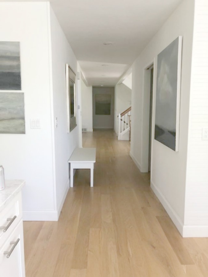 Serene tranquil white kitchen with farm sink, marble subway tile, Viatera Minuet quartz counters, white Shaker cabinets, and white oak flooring. Design and photo: Hello Lovely Studio. #kitchendesign #whitekitchen #minuet #whitequartz #benjaminmoorewhite