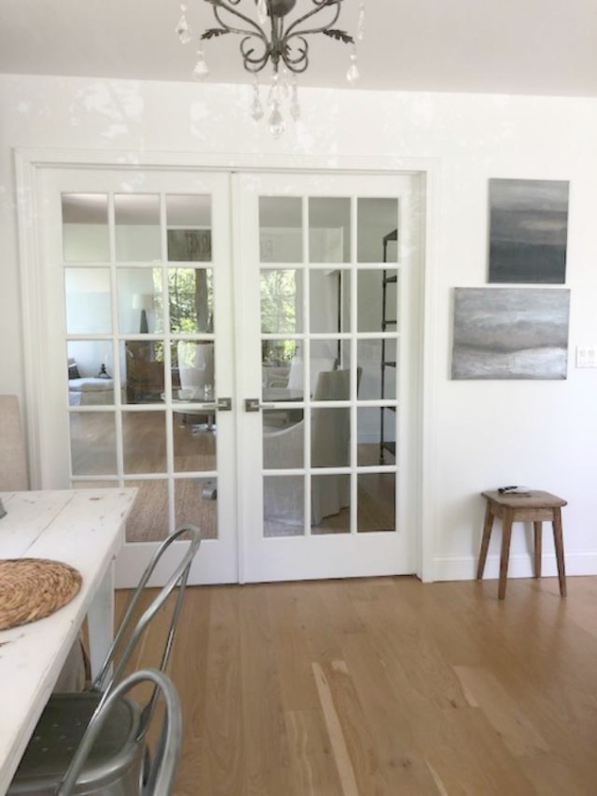 Serene tranquil white kitchen with farm sink, marble subway tile, Viatera Minuet quartz counters, white Shaker cabinets, and white oak flooring. Design and photo: Hello Lovely Studio. #kitchendesign #whitekitchen #minuet #whitequartz #benjaminmoorewhite