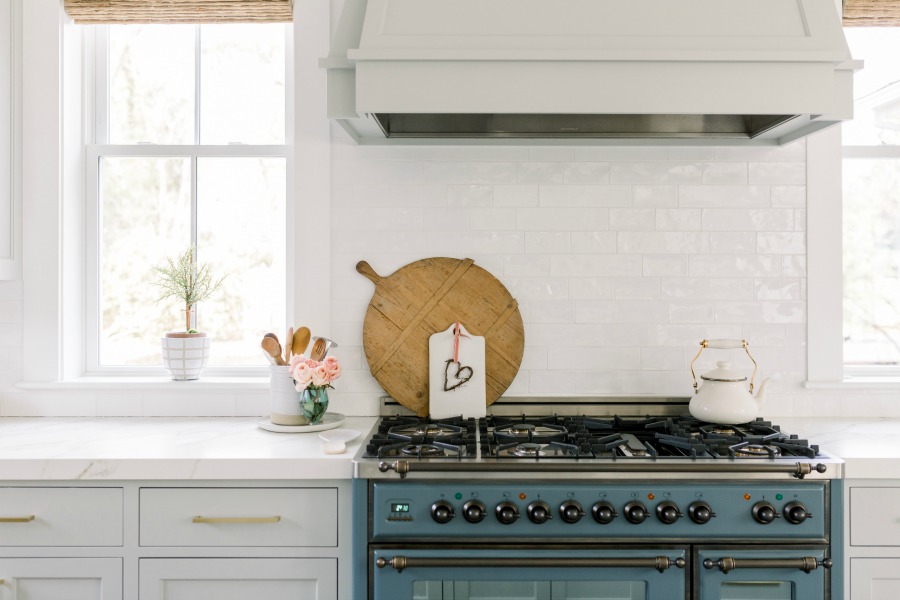 Elegant white farmhouse kitchen with Benjamin Moore Repose Grey cabinets, subway tile, gold accents, and reclaimed barn wood. Design: Finding Lovely. Wall color: Benjamin Moore Chantilly Lace.