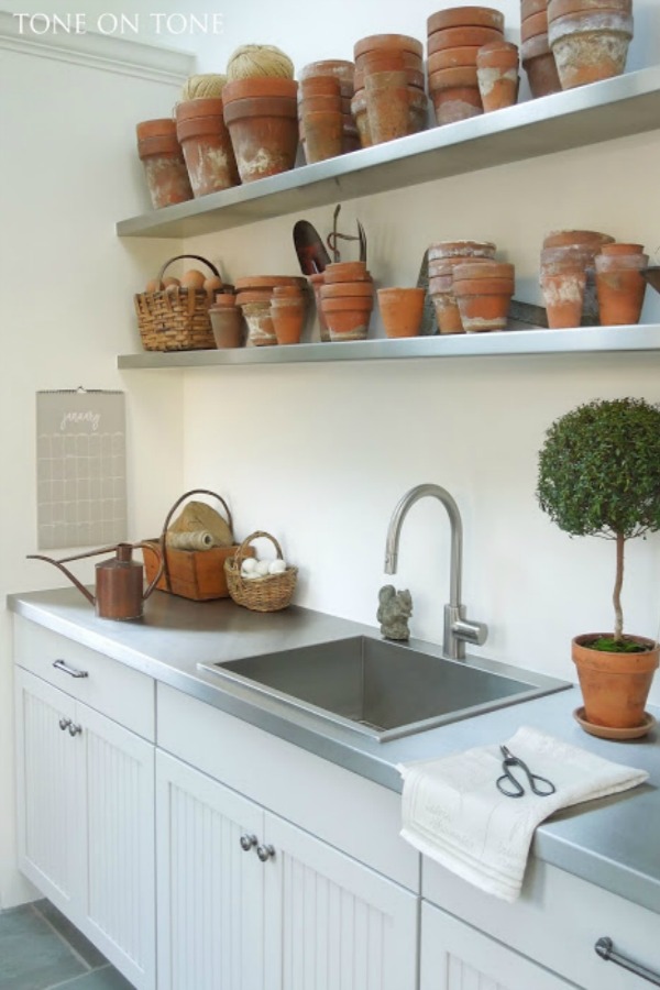 Potting shed gardening shed interior with shelves of terracotta pots, stainless sink, and topiaries - Tone on Tone Antiques. Come explore She Shed Chic, Potting Shed & Backyard Inspiration.