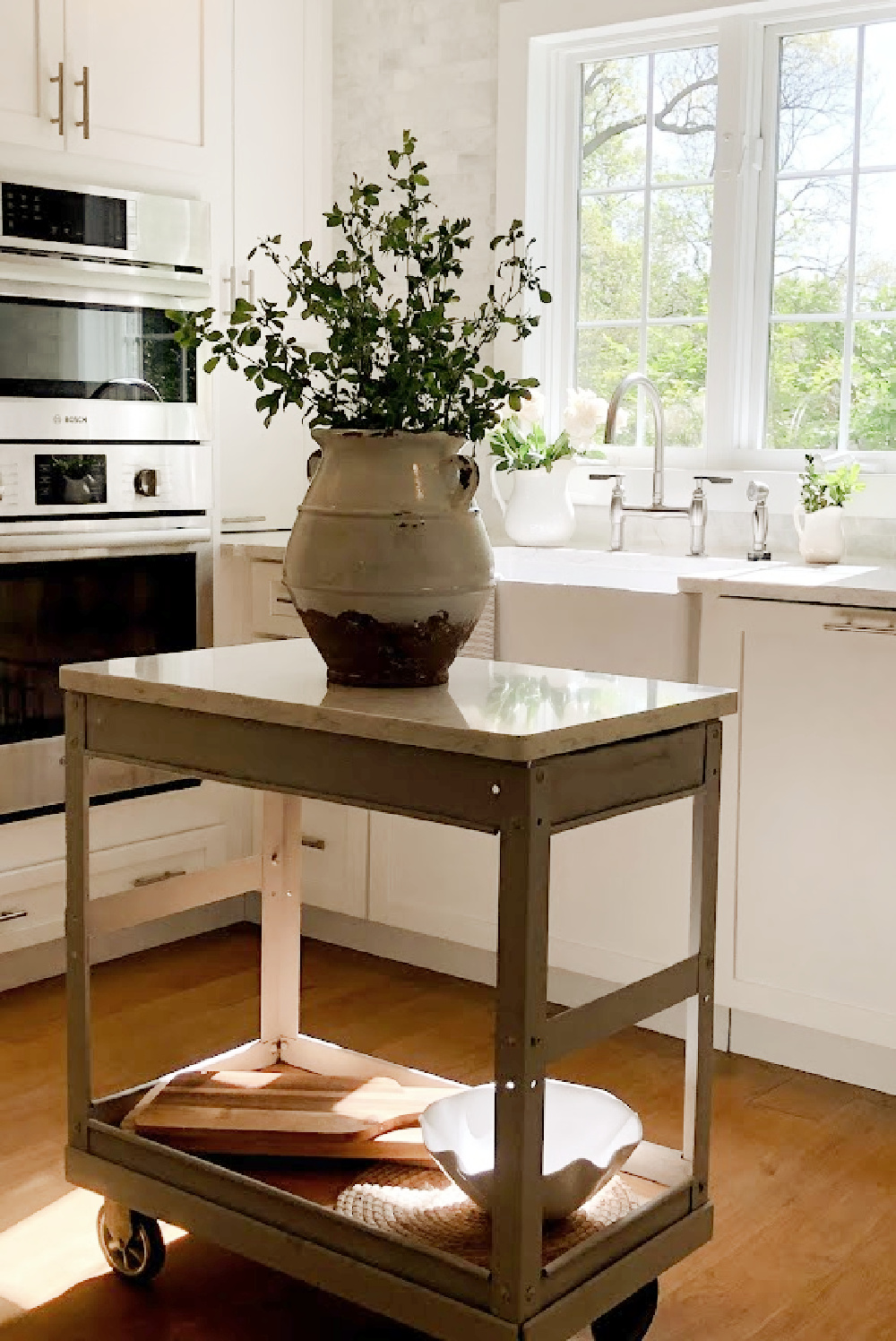 Hello Lovely's white European country modern French kitchen with Minuet Viatera quartz counters, farm sink, industrial cart, and marble subway backsplash.