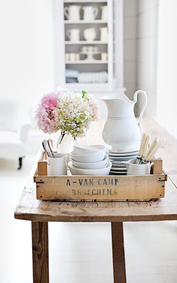 Rustic White French Farmhouse style vignette with Belgian crate, ironstone, and hydrangea upon a wood table. Dreamy Whites Atelier. #frenchfarmhouse #interiordesign #rusticdecor #frenchcountry