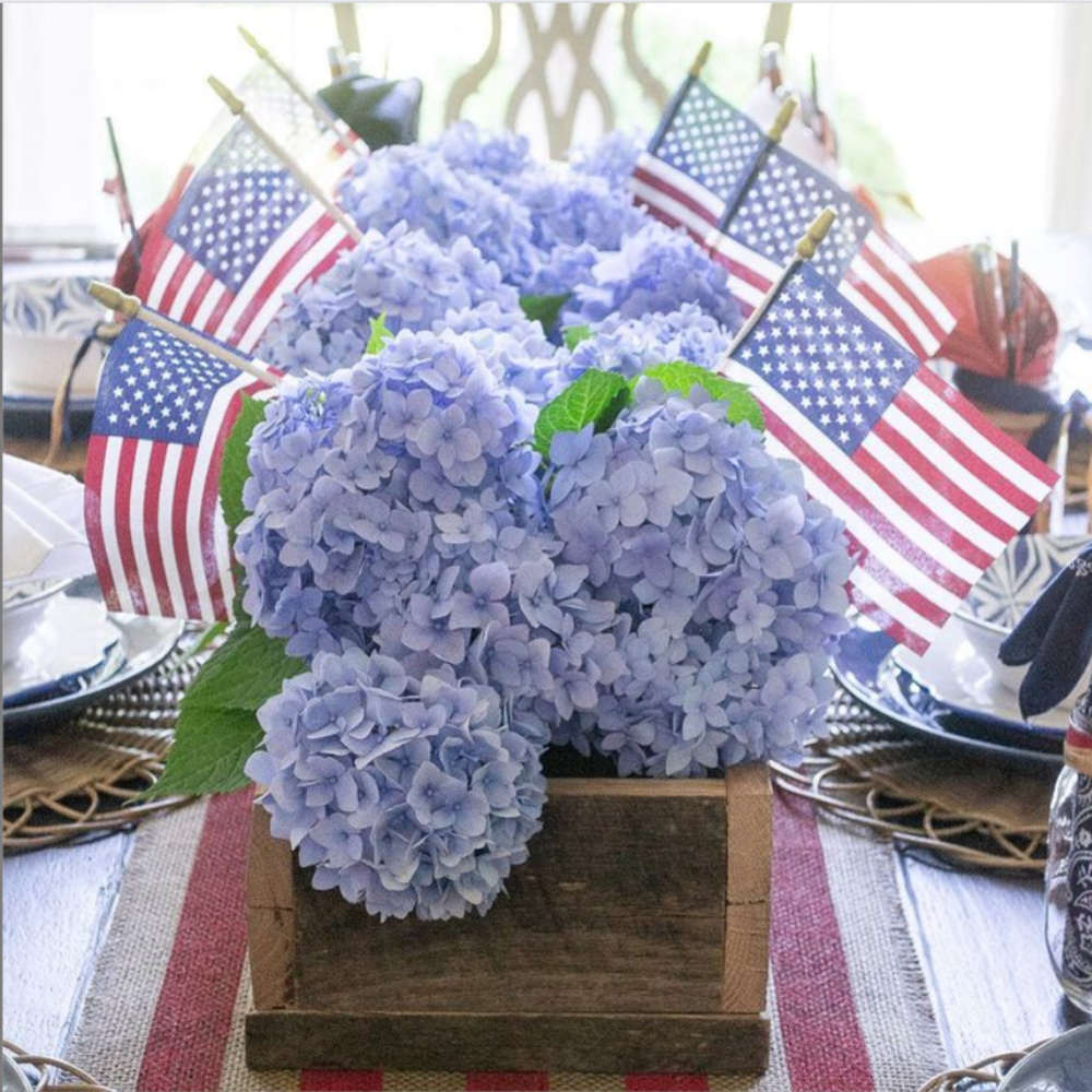 Blue hydrangea 4th of July centerpiece with American flags on table - @houseofelynryn. #centerpieces #tablescapes #july4 #hydrangea