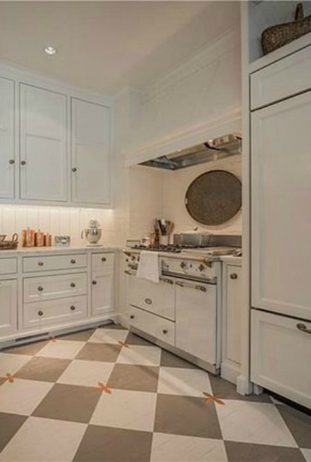 Checkered wood floor and white Lacanche range in beautiful French country kitchen of an elegant historic home with Old World style and beautifully classic European inspired interiors in Marietta Georgia was built for the Kennedy-DuPre family. ee more of the Entry, Living Room & Kitchen Design Inspiration As Well As Photos of a Beautiful Georgia Tudor Exterior on Hello Lovely Studio.