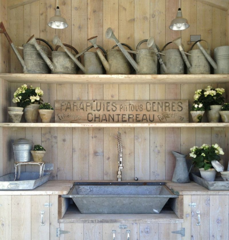 Vintage galvanized watering can collection and French antique sign in garden shed at Patina Farm, a European country French farmhouse inspired home by Brooke Giannetti and Steve Giannetti. #wateringcans #frenchfarmhouse #gardenshed #patinafarm