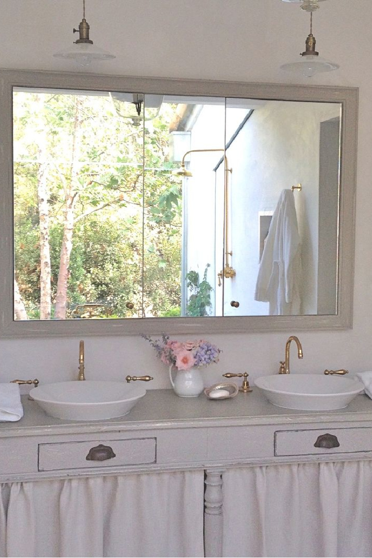 French farmhouse style bathroom vanity made from repurposed antique with linen curtains to hide storage - Brooke Giannetti designed for Patina Farm. #bathroom #patinafarm #frenchfarmhouse #interiordesign #bathroomdesign #oldworld #antiques