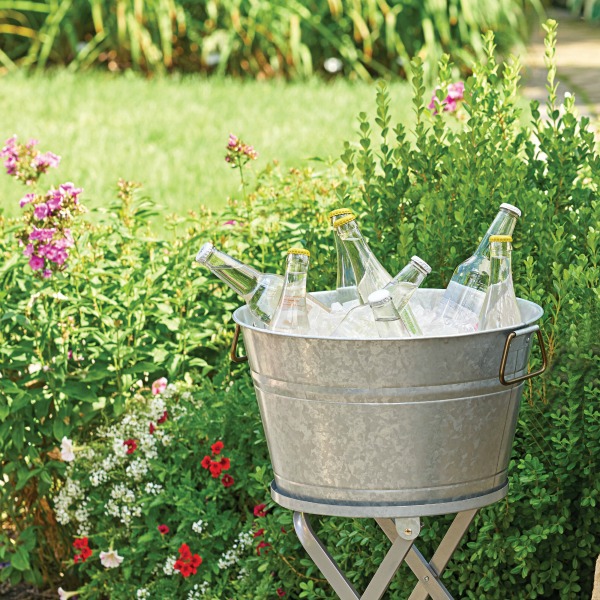 Galvanized round tub with ice and cold drinks ready for a party in summer. Come see my Farmhouse French Inspired Courtyard, Inexpensive Bistro Dining Sets & Garden Finds.