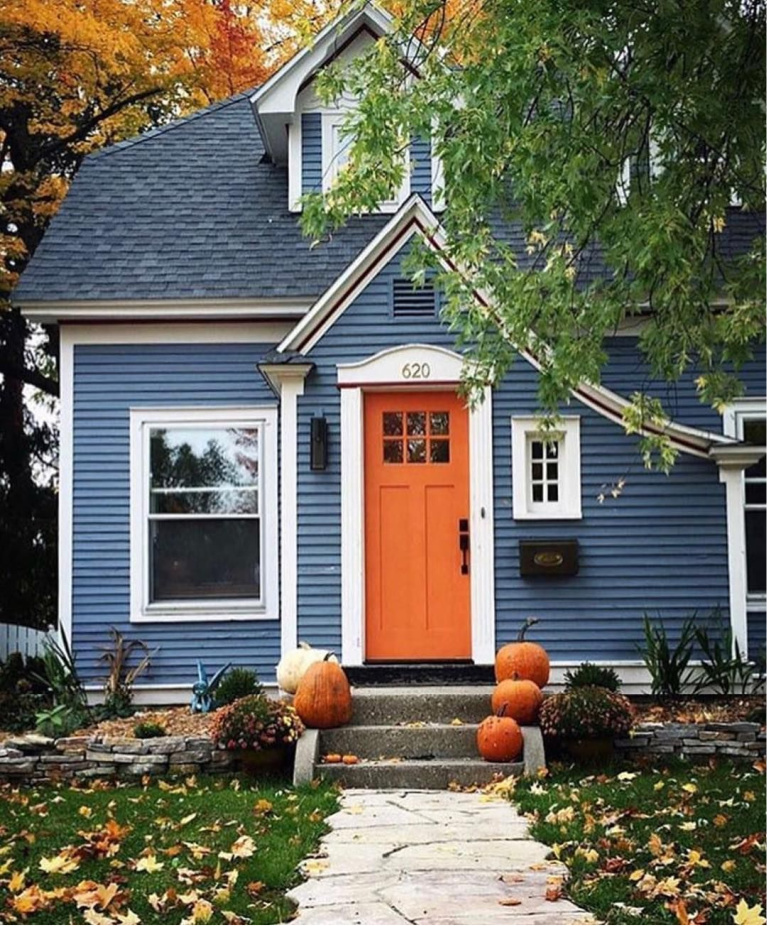 Indigo blue Tudor style house with bright orange door in fall with leaves and pumpkins - Bobby's Girl. #houseexteriors #bluehouse #indigoblue #navyblue #blueandorange #fallcurbappeal #frontfacade