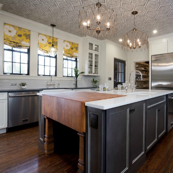 Beautiful renovated white classic kitchen in Julian Price Mansion with subway tile, farm sink, and yellow accents. Marsh Kitchens executed the lovely design which features black windows, warm wood floors, butcher block insert in huge island, and luxury range and hood.