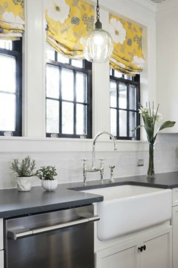 Beautiful renovated white classic kitchen with subway tile, farm sink, and yellow accents. Marsh Kitchens executed the lovely design which features black windows, warm wood floors, butcher block insert in huge island, and luxury range and hood.