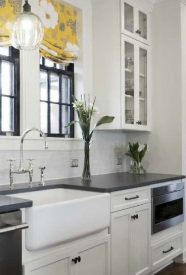 Beautiful renovated white classic kitchen in Julian Price Mansion with subway tile, farm sink, and yellow accents. Marsh Kitchens executed the lovely design which features black windows, warm wood floors, butcher block insert in huge island, and luxury range and hood.