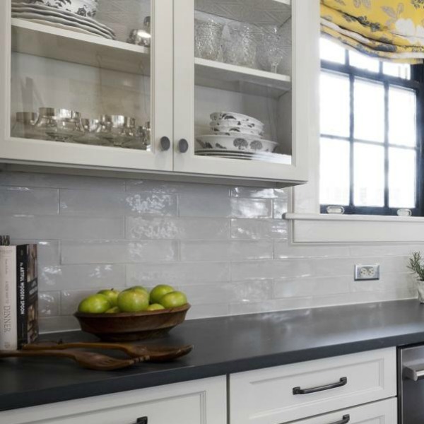 Beautiful design details in the renovated white classic Julian Price House kitchen with subway tile, farm sink, and yellow accents. Marsh Kitchen & Bath executed the lovely design which features black windows, warm wood floors, butcher block insert in huge island, and luxury range and hood.