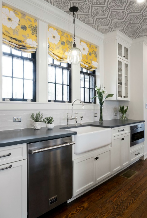 Beautiful design details in the renovated white classic Julian Price House kitchen with subway tile, farm sink, and yellow accents. Marsh Kitchen & Bath executed the lovely design which features black windows, warm wood floors, butcher block insert in huge island, and luxury range and hood.