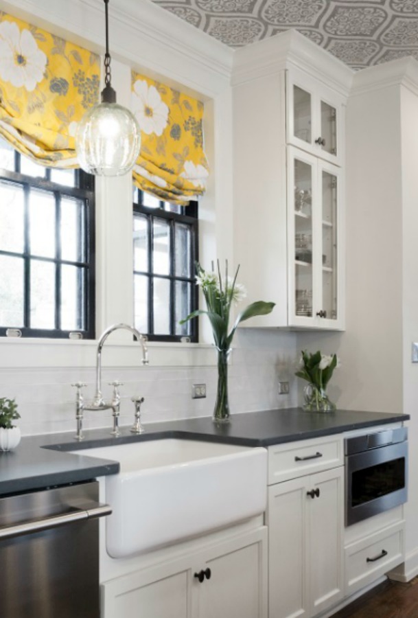 Beautiful renovated white classic kitchen in Julian Price Mansion with subway tile, farm sink, and yellow accents. Marsh Kitchens executed the lovely design which features black windows, warm wood floors, butcher block insert in huge island, and luxury range and hood.