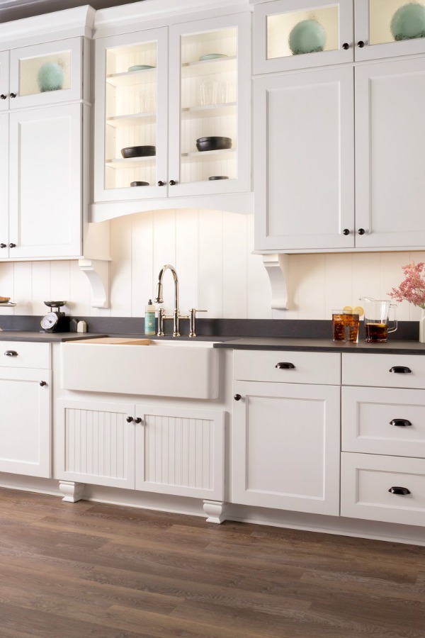 Beautiful kitchen design with white Shaker cabinets, apron front farm sink, and dark counters by Marsh Kitchens on Hello Lovely.