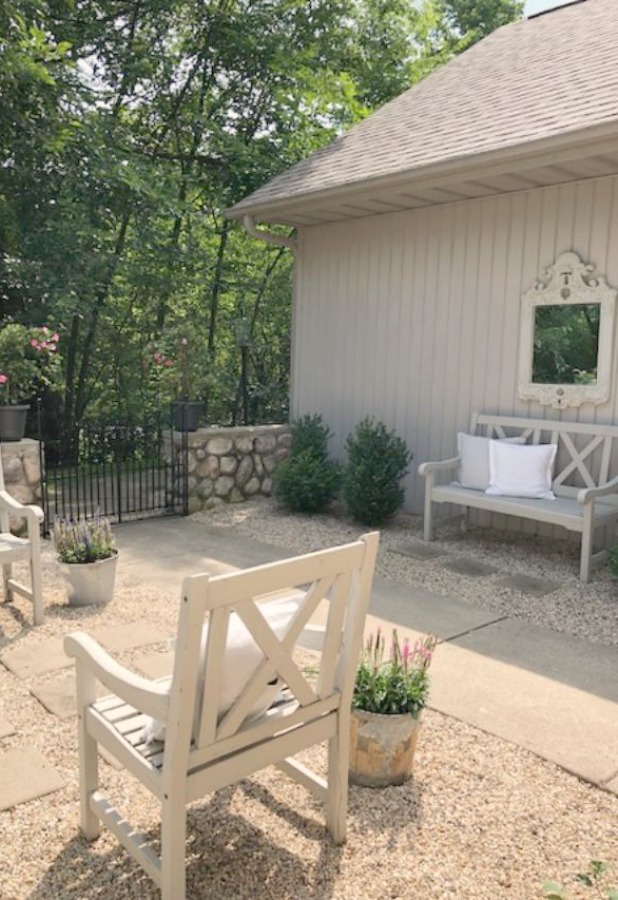 My French farmhouse inspired courtyard in summer with pea gravel, ferns, galvanized buckets, and boxwood - Hello Lovely Studio.