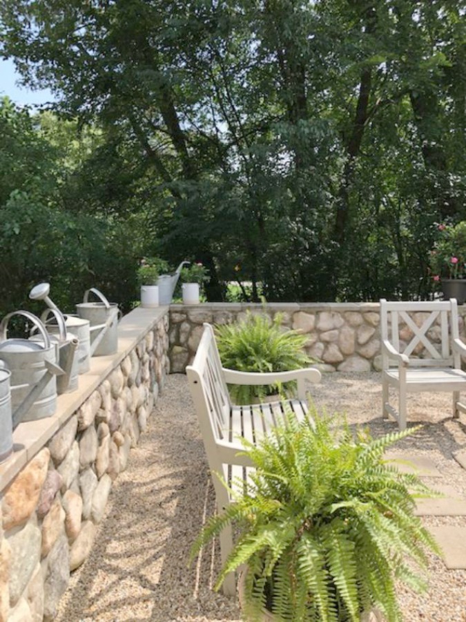 My French farmhouse inspired courtyard in summer with pea gravel, ferns, galvanized buckets, and boxwood - Hello Lovely Studio.