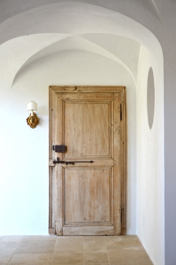 Old World style reclaimed wood door from Europe leads to the laundry room at Patina Farm by Giannetti Home.