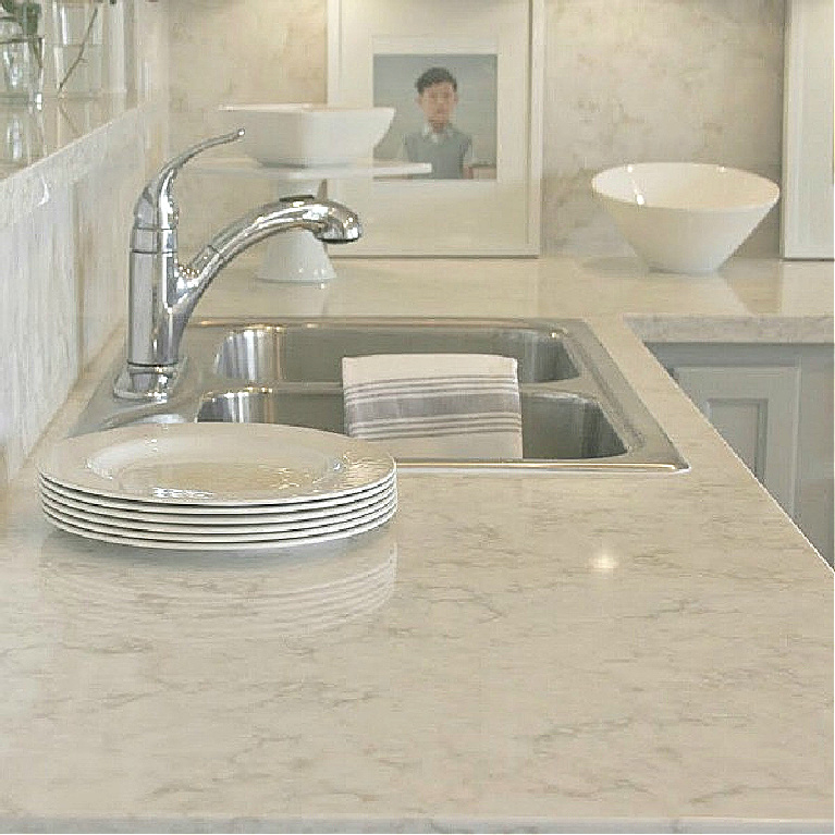 Serene kitchen makeover with Viatera white quartz (Soprano), painted cabinets (Behr Classic Silver), hardware (Top Knobs), and Kitchenaid Smudgeproof appliances - Hello Lovely Studio. #kitchenmakeover #beforeafter #diykitchenreno #kitchendesign #paintedcabinets #viateraquartz #soprano #homereno