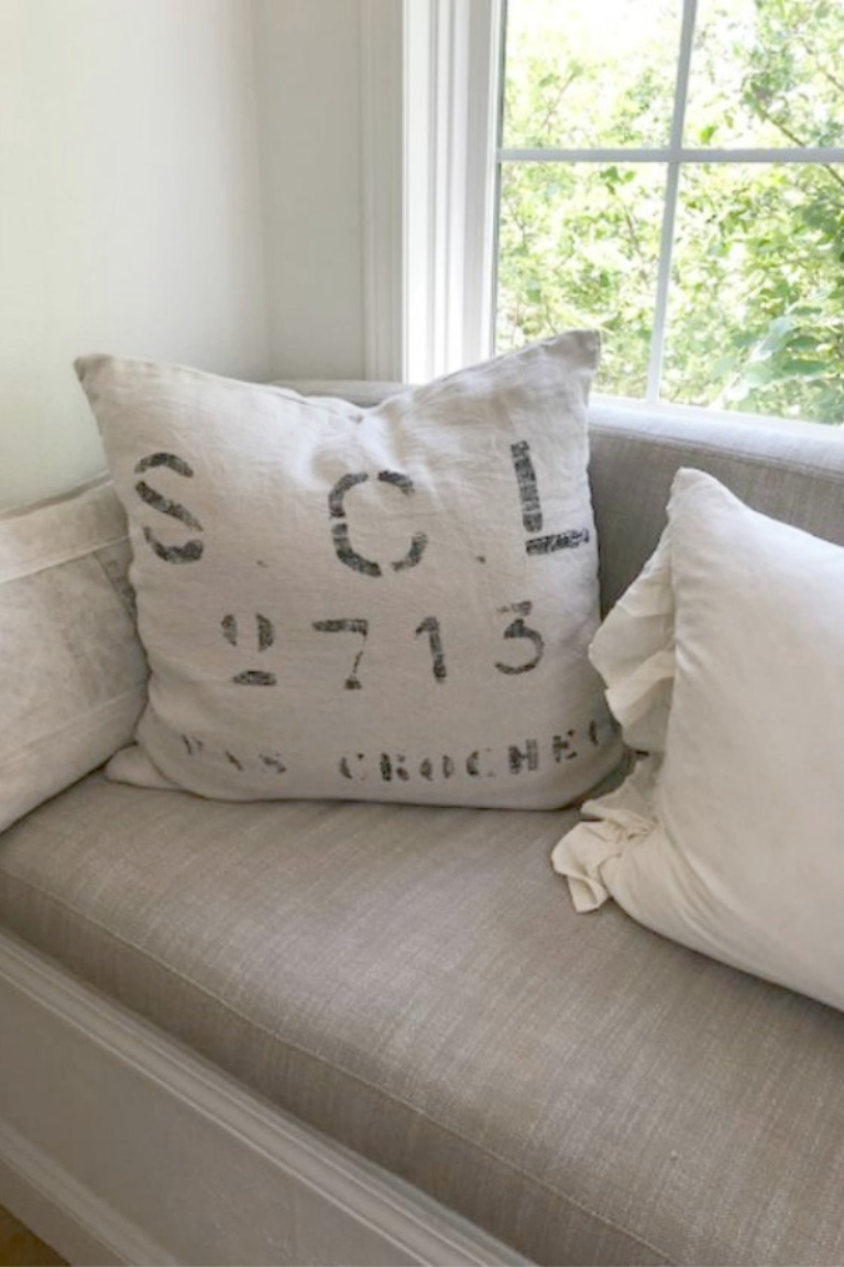 Detail of grainsack pillow and Belgian linen cushion on the window seat in Hello Lovely's kitchen. Find a Soft, Ethereal European Country Kitchen Mood to Inspire Now!