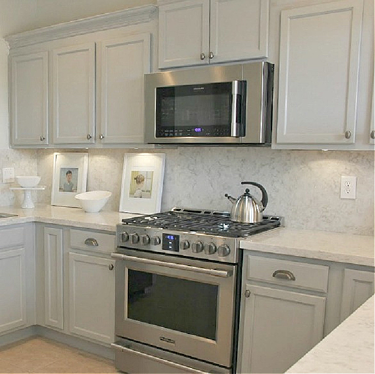 Serene kitchen makeover with Viatera white quartz (Soprano), painted cabinets (Behr Classic Silver), hardware (Top Knobs), and Kitchenaid Smudgeproof appliances - Hello Lovely Studio. #kitchenmakeover #beforeafter #diykitchenreno #kitchendesign #paintedcabinets #viateraquartz #soprano #homereno