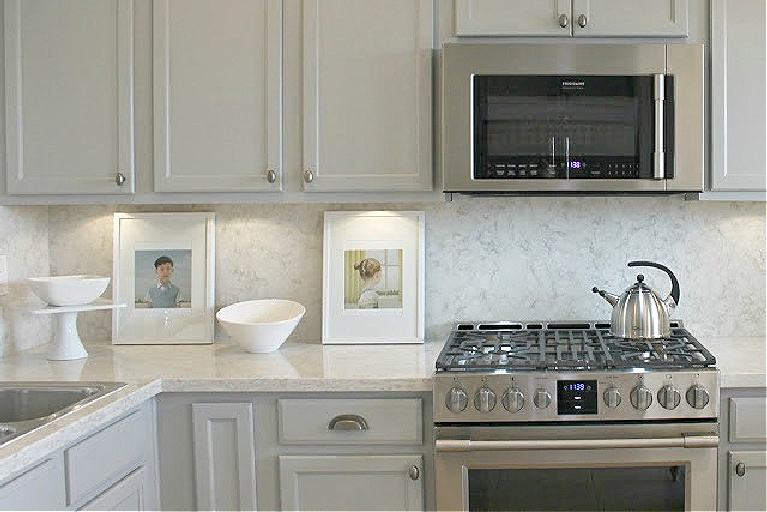 Serene kitchen makeover with Viatera white quartz (Soprano), painted cabinets (Behr Classic Silver), hardware (Top Knobs), and Kitchenaid Smudgeproof appliances - Hello Lovely Studio. #kitchenmakeover #beforeafter #diykitchenreno #kitchendesign #paintedcabinets #viateraquartz #soprano #homereno