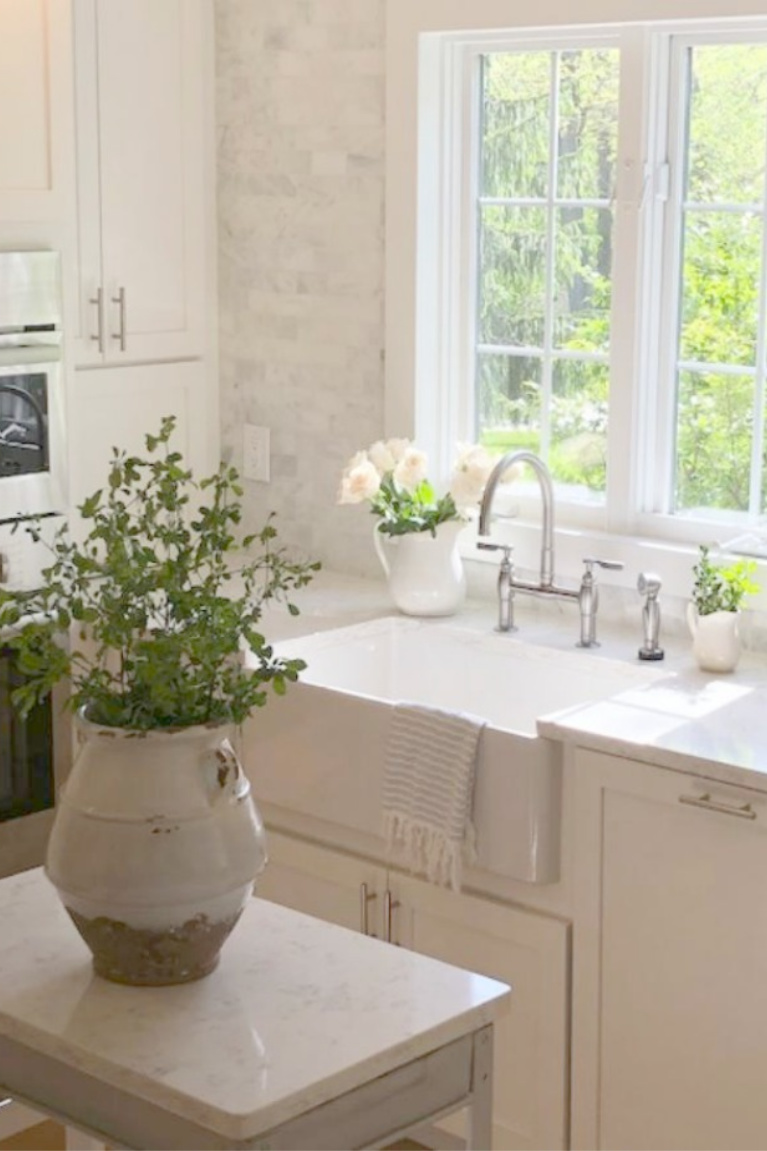 Serene white Shaker kitchen with fireclay farm sink and vintage work cart. Viatera Minuet quartz on counters. #hellolovelystudio #kitchendesign #serenedecor #viatera #minuet #farmsink #reinhard