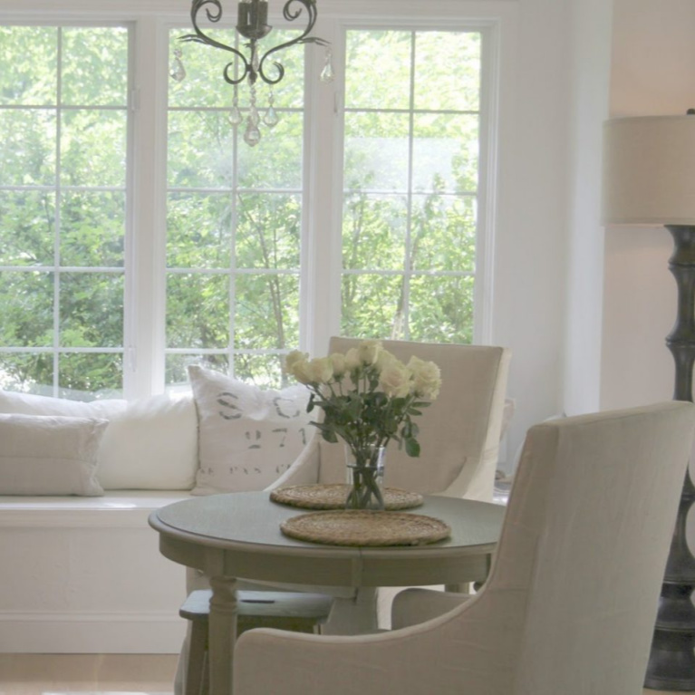 Window seat with European inspired pillows and Belgian linen slipcovered dining chairs in a breakfast area of a French country kitchen - Hello Lovely Studio. #frenchcountry #kitchendesign #breakfastroom #belgianlinen #windowseat #serenedecor