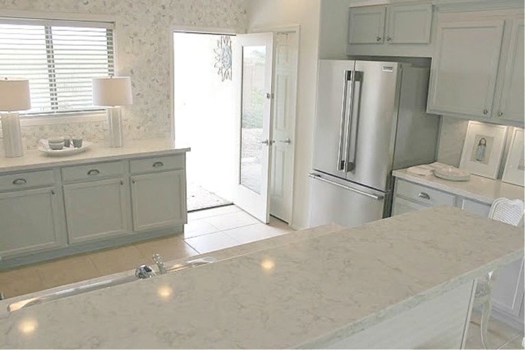 Serene kitchen makeover with Viatera white quartz (Soprano), painted cabinets (Behr Classic Silver), hardware (Top Knobs), and Kitchenaid Smudgeproof appliances - Hello Lovely Studio. #kitchenmakeover #beforeafter #diykitchenreno #kitchendesign #paintedcabinets #viateraquartz #soprano #homereno