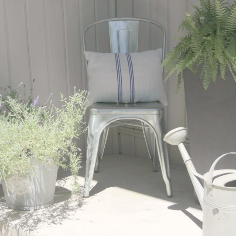 Industrial farmhouse metal chair with a grainsack cushion on my front porch with vintage watering can. #hellolovelystudio #frenchfarmhouse #metalchair #vintagestyle #wateringcan #outdoordecor