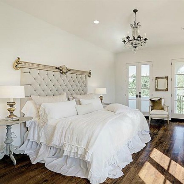 Beautiful all white French country bedroom with tufted velvet headboard and warm wood floors. See more elegant white country interiors in this story!