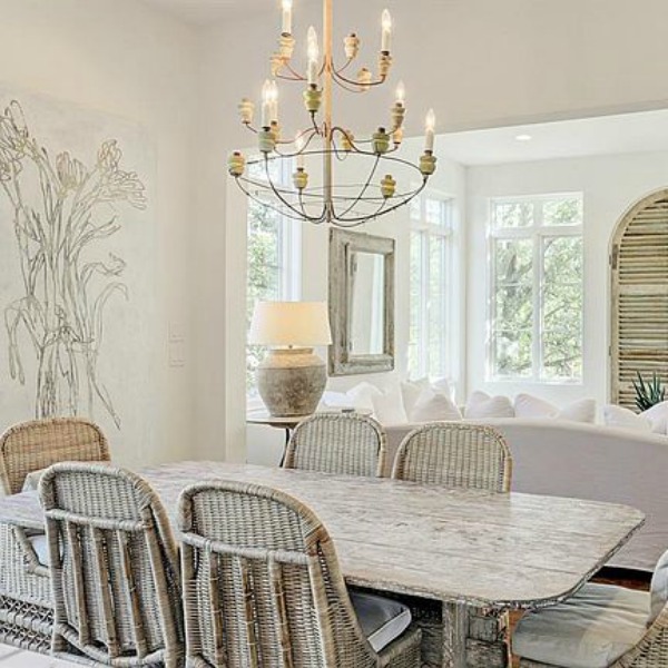 Rustic wood farmhouse dining table and rattan chairs add charming texture to a country French home in Houston. Find more airy, light, white, and bright country rooms to inspire in this post!