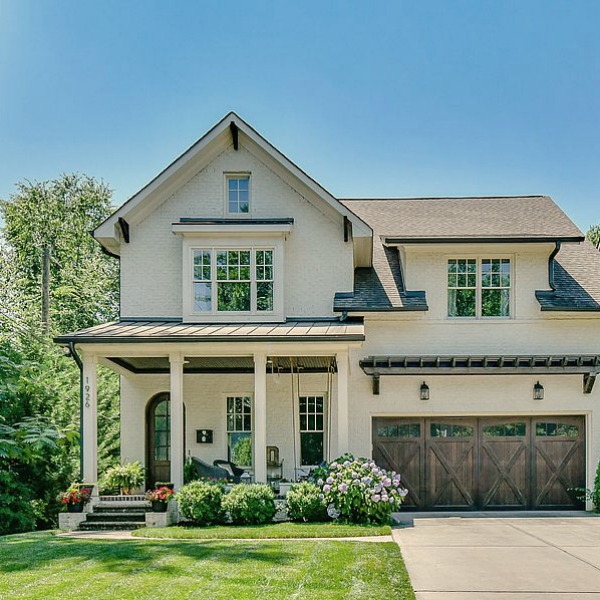 This charming home exterior in Charlotte, NC, boasts curb appeal, traditional design, and inspiring architectural details - Hello Lovely Studio. Try BM Revere Pewter for a comparable exterior color. White Homes + A Few Bright White Exterior Paint Colors