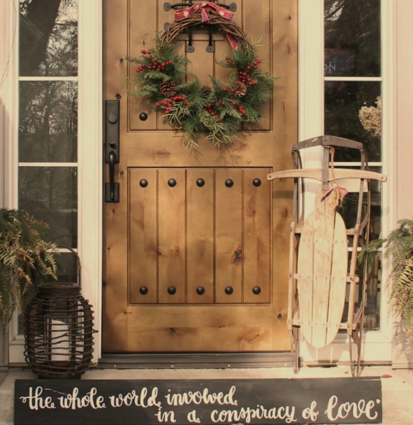 Christmas wreath on my front door with a vintage sled and wood lantern - Hello Lovely Studio. #christmasdecor 