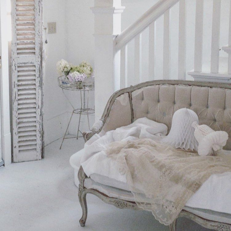 All white French Nordic decor, antiques, and interior design style in this breathtaking cottage with tufted French settee, crepe paper bells, and distressed shutter - My Petite Maison.