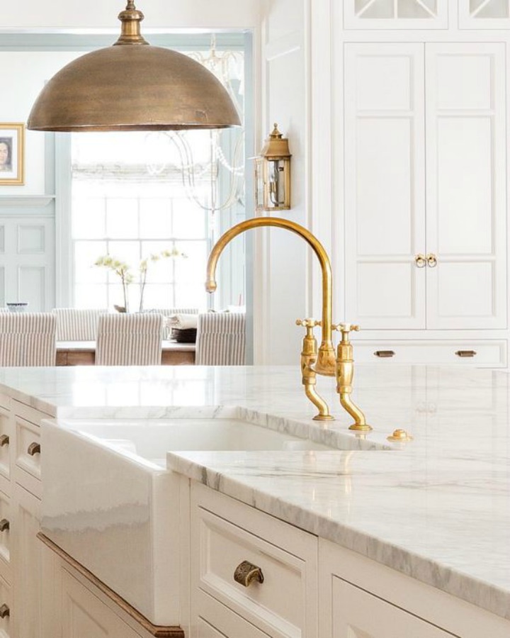 Beautiful white timeless kitchen with marble countertop, brass kitchen faucet, and dome pendant - design by The Fox Group.