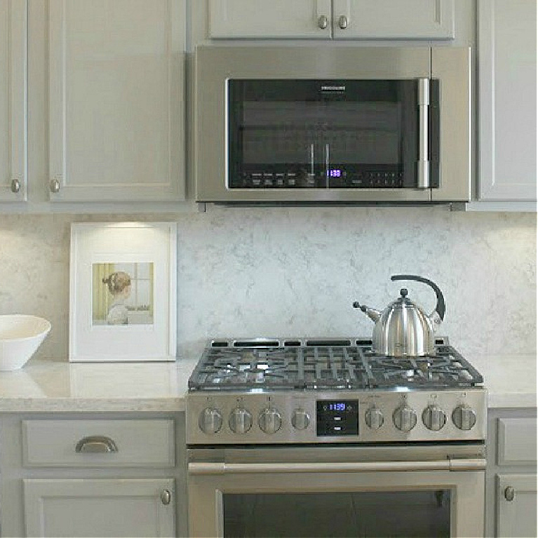 Behr Classic Silver paint color on kitchen cabinets in Hello Lovely's serene kitchen makeover with Viatera Soprano quartz. #hellolovelystudio #kitchendesign #paintcolors #behrclassicsilver #viaterasoprano #quartzcountertop #quartzbacksplash #kitchenaidappliances