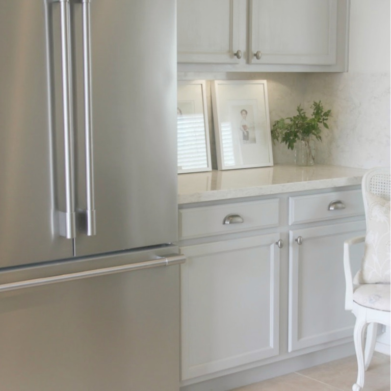 Behr Classic Silver paint color on kitchen cabinets in Hello Lovely's serene kitchen makeover with Viatera Soprano quartz. #hellolovelystudio #kitchendesign #paintcolors #behrclassicsilver #viaterasoprano #quartzcountertop #quartzbacksplash #kitchenaidappliances