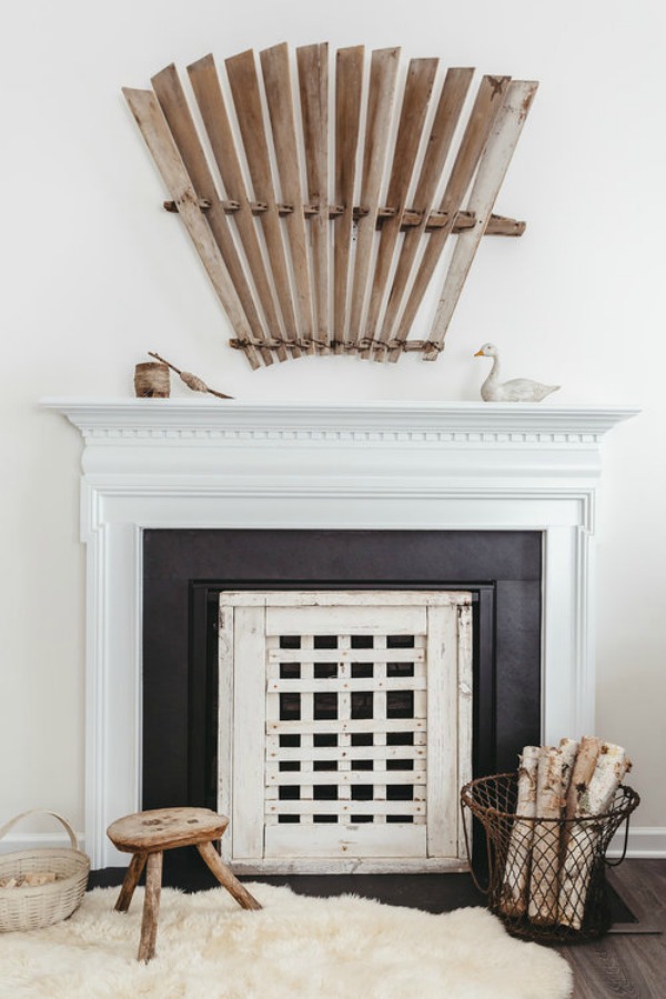 A white fireplace with black stone and country decor in a lovely interior by City Farmhouse.