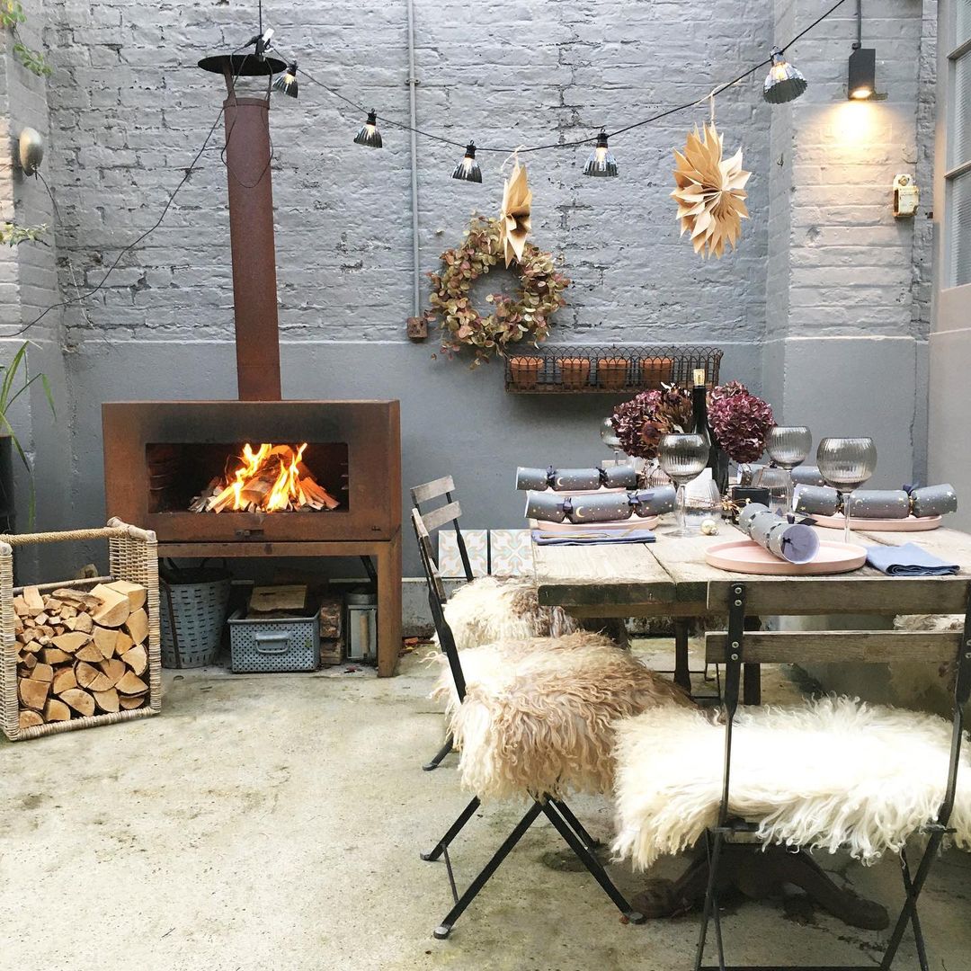 English country courtyard with fireplace and dining chairs covered with sheepskins - Imperfect Interiors. #englishcountry #courtyard #outdoordining #wintercourtyard