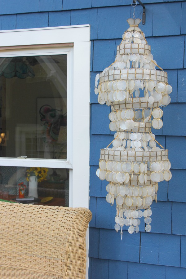 Capiz shell pendant against bold blue cedar shake siding of a cottage by Jenny Sweeney.