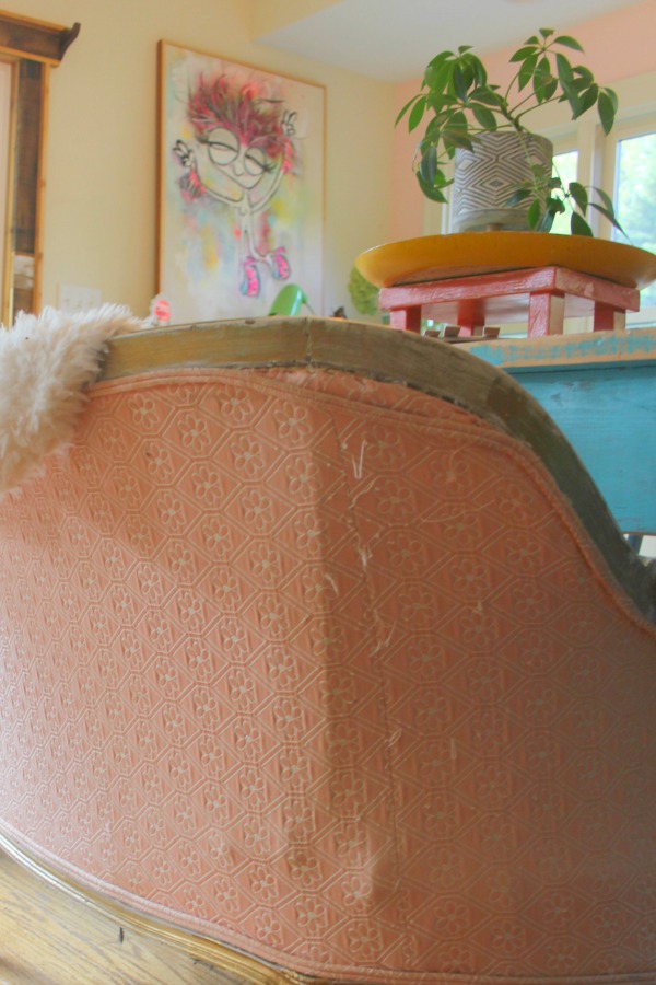 Vintage pink settee with sheepskin at a rustic farm table in a cottage by Jenny Sweeney.