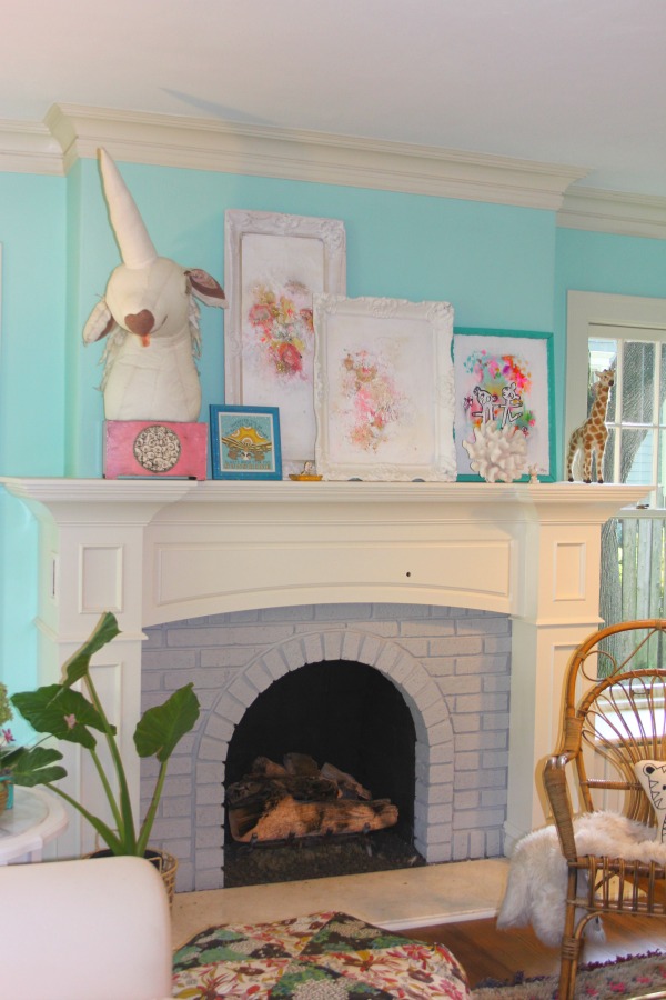 Whimsical art by Jenny Sweeney lines the fireplace mantel in a quirky Libertyville, IL cottage.