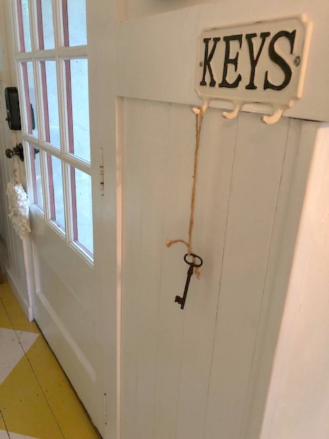 Farmhouse charm and vintage style in a charming entry with white paneling and bold yellow painted poplar floors greeting you at Storybook Cottage in Leiper's Fork near Franklin, TN. The interiors designed by Kim Leggett of City Farmhouse inspire! #farmhousedecor #storybookcottage #entry