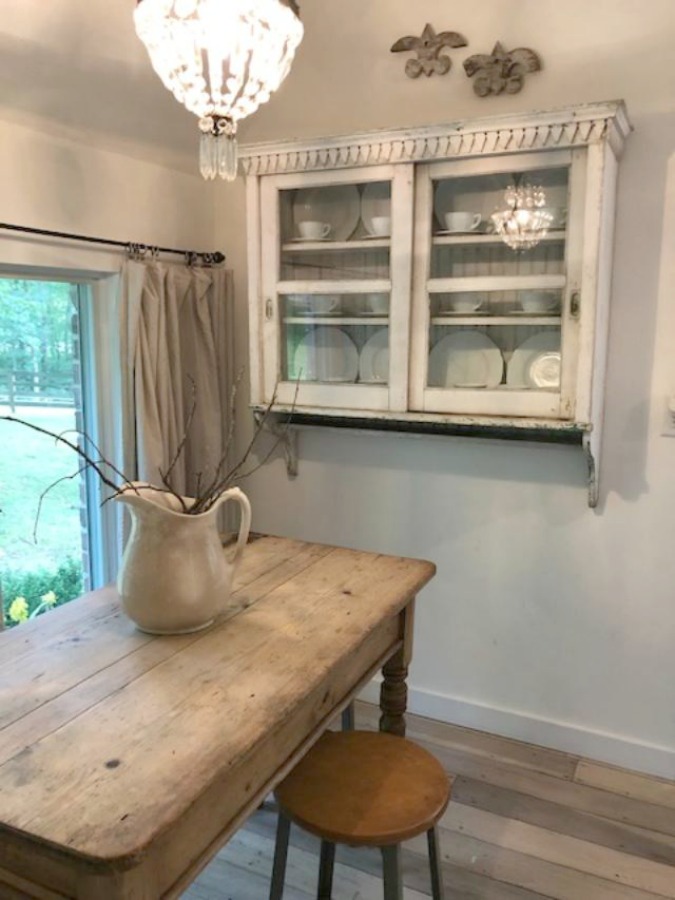 From the blue grey cabinet doors with cross cut out detail to the open shelving, this farmhouse kitchen designed by City Farmhouse for Storybook Cottage in Leiper's Fork, TN, sings with vintage country style! Photo by Hello Lovely Studio. #farmhousekitchen #cityfarmhouse #storybookcottage