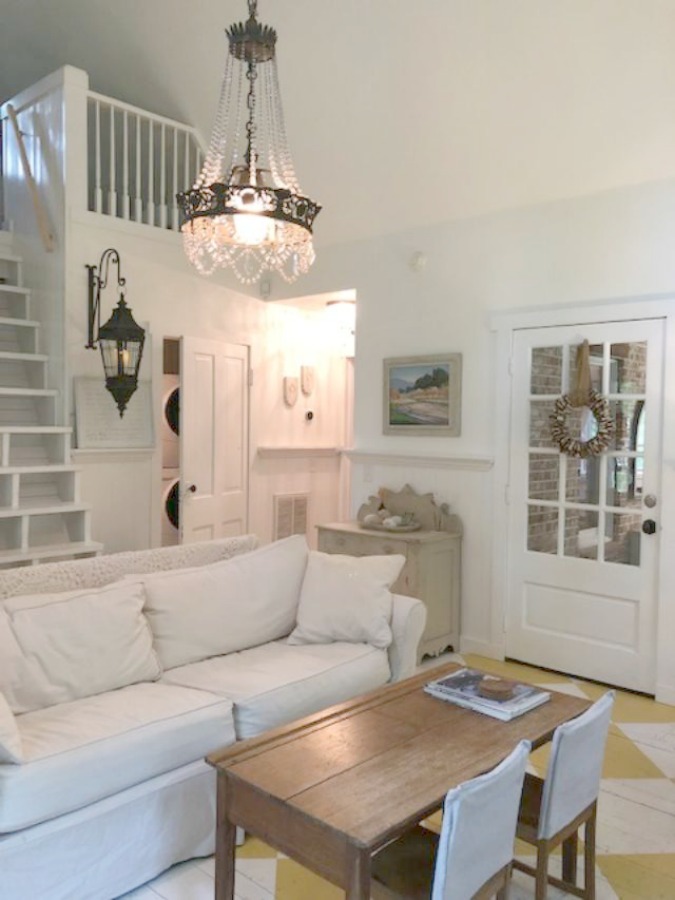 Farmhouse chic living room with vintage treasures, bold yellow painted poplar wood flooring, linen upholstery, and design by City Farmhouse for Storybook Cottage in Leiper's Fork, TN - Hello Lovely Studio. #farmhousestyle #livingroom #cityfarmhouse #storybookcottage